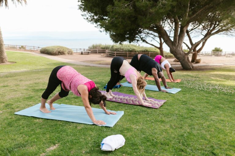 Group practicing yoga outdoors in a park, focusing on balance and fitness.