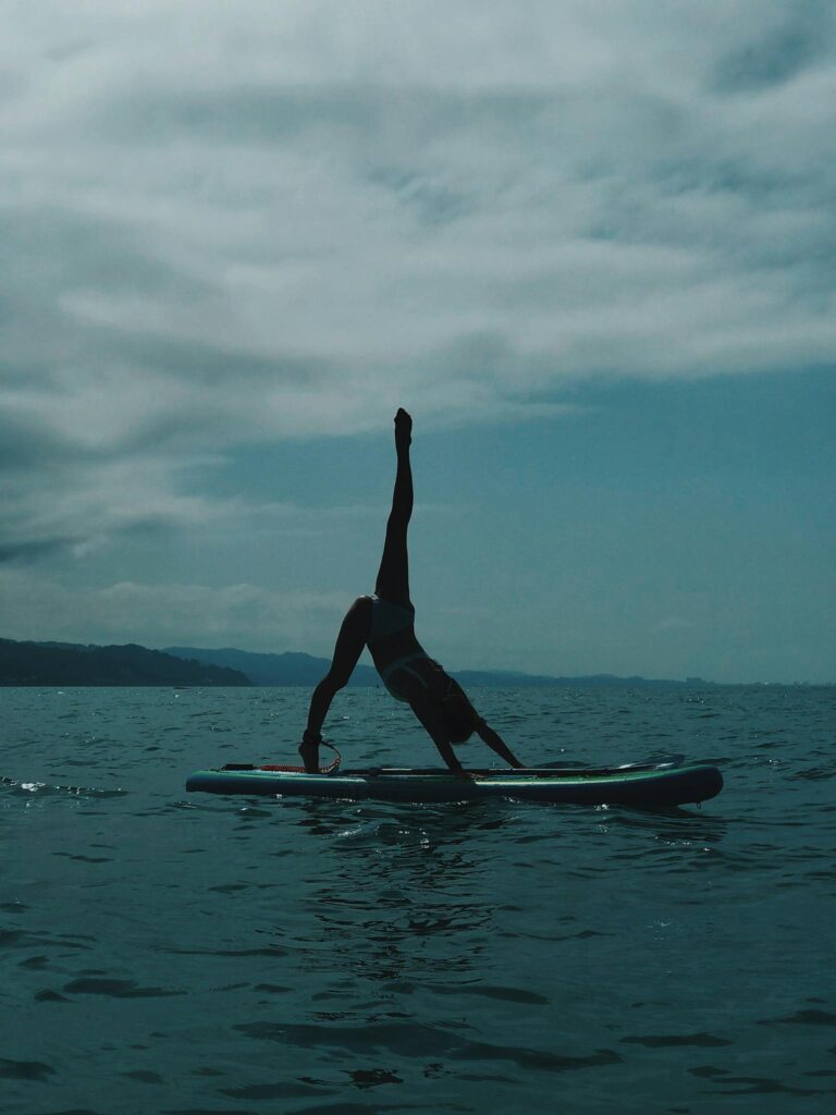 Silhouette of woman doing yoga pose on paddleboard in Sochi's sea.