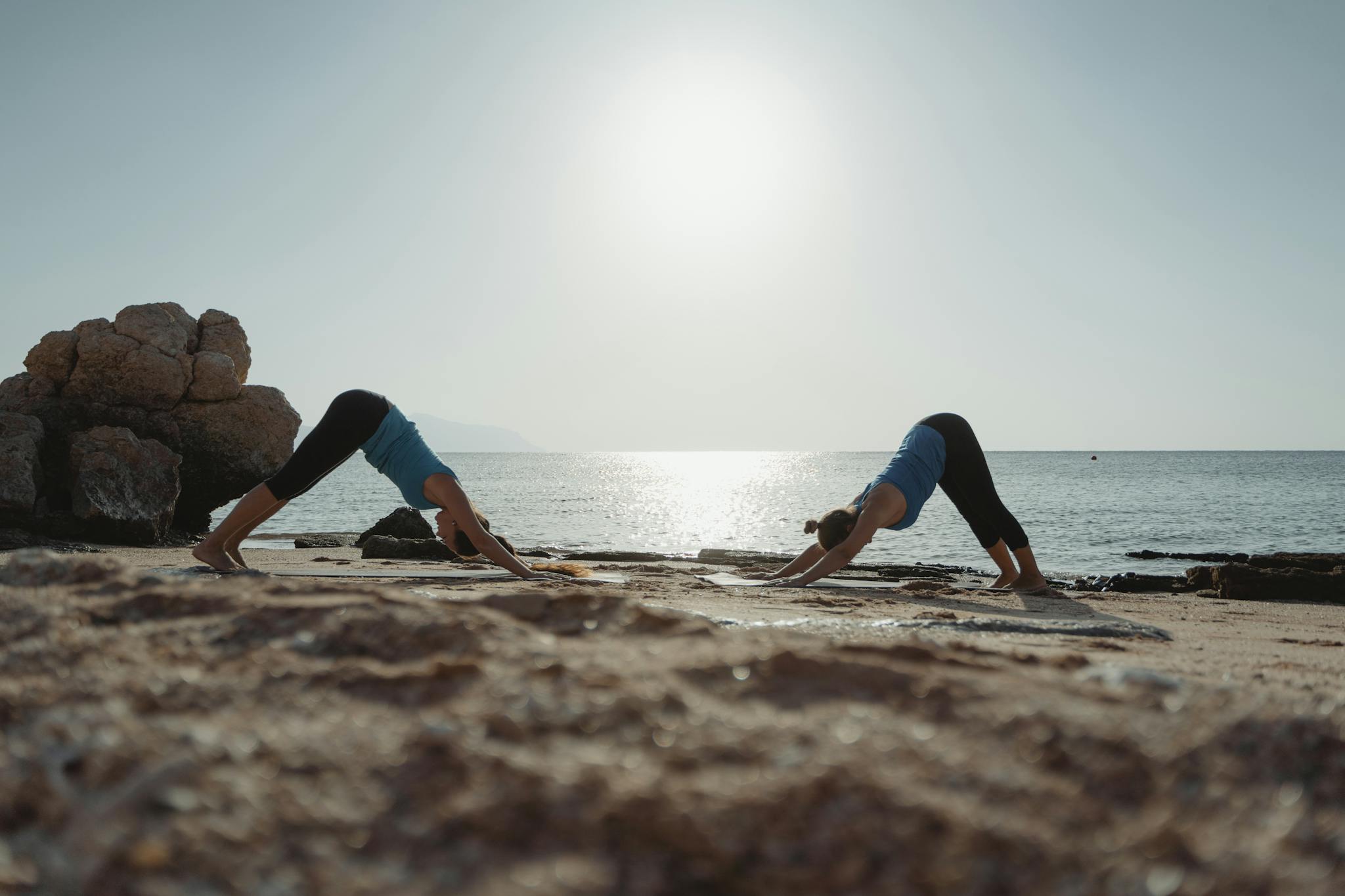 Photo by Tima Miroshnichenko Two women practicing yoga at dawn on a serene beach with clear waters.